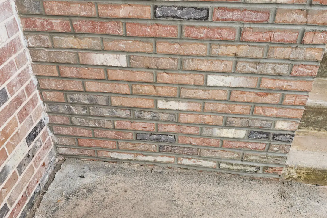 A brick wall after repointing, the new joints packed and struck flush between the original brick.